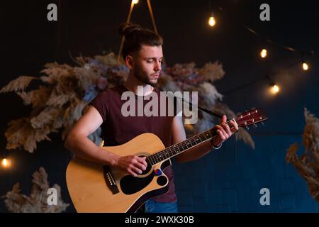 Male musician playing acoustic guitar. Guitarist plays classical guitar on stage in concert Handsome male guitar player perform private party Stylish long hair Medium shoot Stock Photo