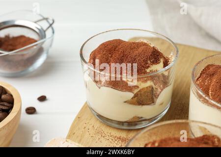 Delicious tiramisu in glasses and coffee beans on white table, closeup Stock Photo