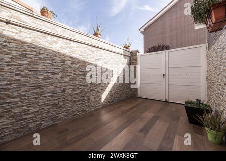 entrance of a multi-story detached house with brick facades of different models, white doors and many different flower pots. Stock Photo