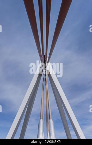 Suspension cables and structure of a small suspension bridge with a metal structure over a road Stock Photo