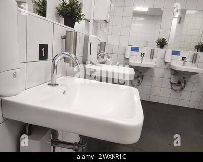 Modern bathroom sink and touchless faucet in public toilet and restroom. Stock Photo