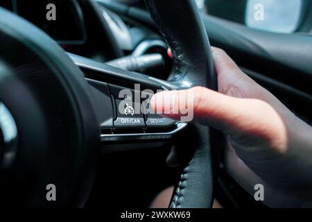 Automotive cruise control system on the steering wheel in a car , driver pressing cruise control button , Automotive technology concept Stock Photo