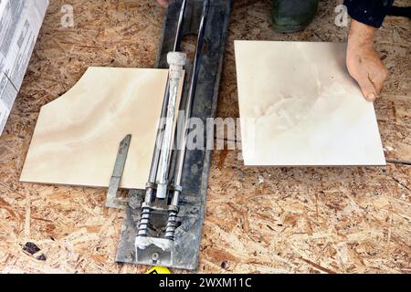 Manual tile cutter cutting machine is used for tiling work, tiler cuts tile in half. Stock Photo