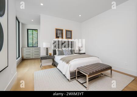 A spacious bedroom featuring a large bed next to a wall lamp. Stock Photo