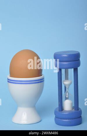Boiled egg and hourglass on a blue background Stock Photo