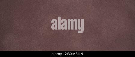 Dark brown matte background of suede fabric, closeup. Velvet texture of seamless deep umber leather with vignette. Felt material macro. Stock Photo