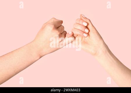 Hands of friends making pinky promise on color background Stock Photo