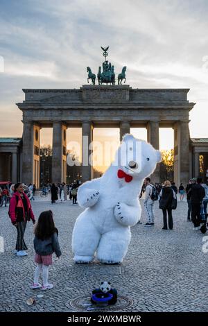 Berlin, Germany. 31st Mar, 2024. A street entertainer, polar bear entertains children at The Brandenburg Gate as The sun sets over the city on Easter Sunday. Credit: Guy Bell/Alamy Live News Stock Photo