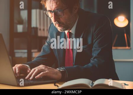 Businessman typing laptop computer keyboard in the office late at night, selective focus Stock Photo