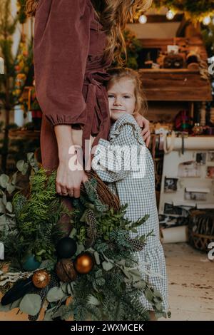 A girl hugging a woman holding a Christmas Wreath Stock Photo