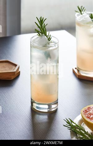 two grapefruit rosemary cocktails with garnish on black table Stock Photo