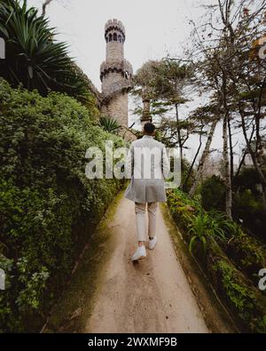 A man in formal attire walking towards a tall tower Stock Photo