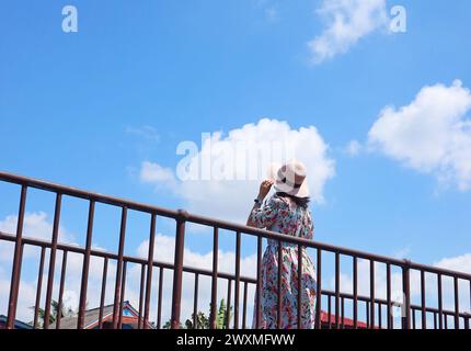 Woman on the bridge looking up to the beautiful sunny sky Stock Photo