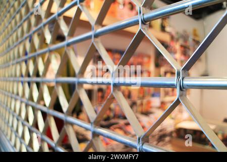 Closed Steel Roller Shutter Door with Blurry Store Interior in Background Stock Photo