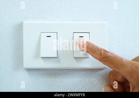 Finger pushing a switch to turn on light Stock Photo