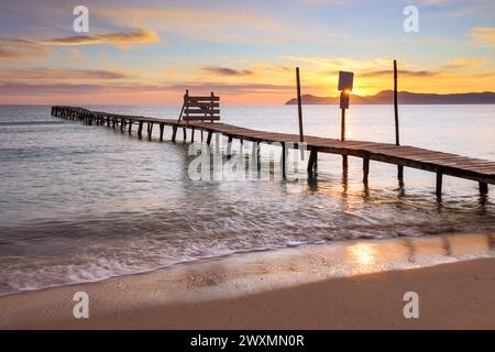 Beautiful sunrise on a beach with old wooden jetty in Platja de Muro, Majorca, Balearic Islands, Spain Stock Photo