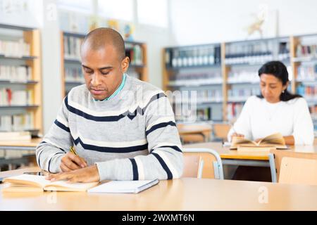 Young adult man studying in public library Stock Photo