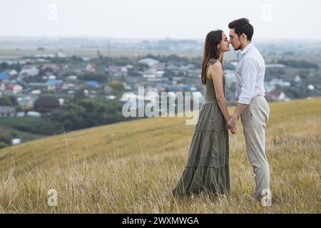 Smiling man and woman kiss holding hands at countryside Stock Photo