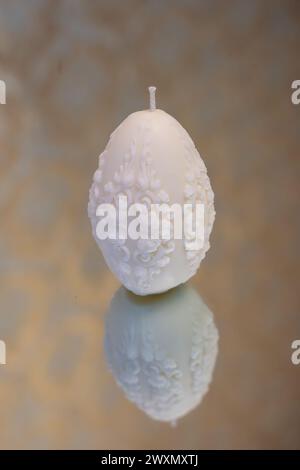 White easter egg soy wax candle. Mirror background Stock Photo