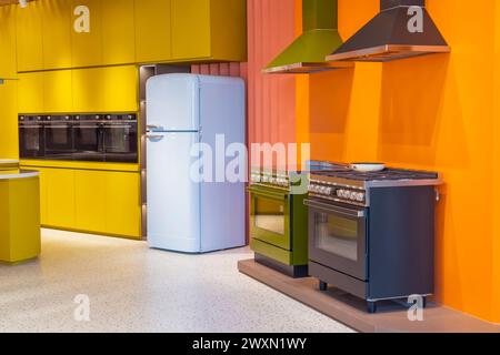 Interior of modern kitchen yellow orange walls two stoves and a hood, light blue refrigerator with a rounded shape, retro vintage style. Stock Photo