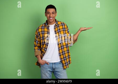 Photo of young cheerful man in plaid shirt demonstrating new modern fpv drone for ukrainian army isolated on green color background Stock Photo