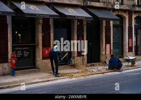 Two workers renovating a traditional tiled sidewalk in Lisbon, Portugal. February 2, 2024. Stock Photo