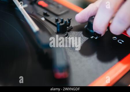 Close-up of a finger adjusting the volume knob on a red portable vinyl turntable Stock Photo