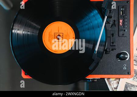 Top-down shot of a vinyl record spinning on a vibrant red portable turntable player Stock Photo
