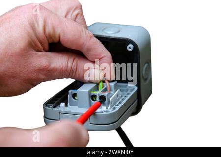 Man wiring an outdoor electric socket using an electrical screwdriver. Isolated on a white background Stock Photo