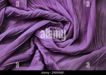 A close-up of purple striped fabric with wave pattern folds and textures Stock Photo