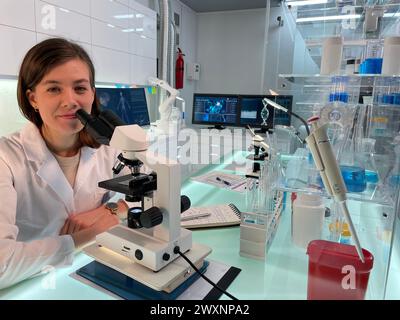 Female scientist using microscope at desk Stock Photo