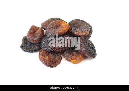 Pile of dark dried brown apricots isolated on white background. Stock Photo