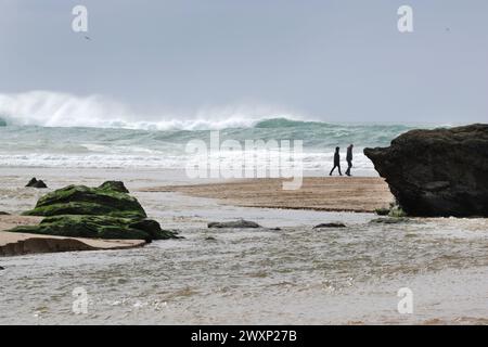 Beach walkers on a windy afternoon, Perranporth, Cornwall Stock Photo