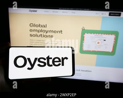 Person holding smartphone with logo of US human resources platform company Oyster HR Inc. in front of website. Focus on phone display. Stock Photo