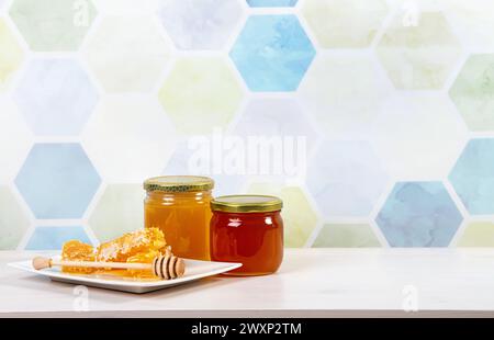 Glass honey jars with different color honey inside, lot of copy space on light blue honeycomb pattern background. Honey border background concept. Stock Photo