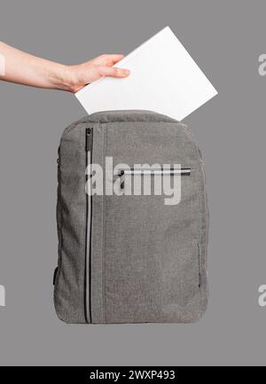 Hand putting blank book into backpack isolated. Stock Photo