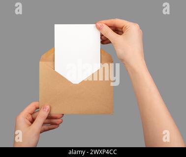 Postcard mockup, vertical blank card taking from paper envelope isolated on white. Stock Photo