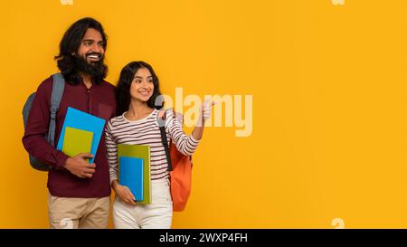 Two students holding books on yellow background Stock Photo