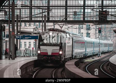 Passenger train is approaching the station of Berlin Friedrichstrasse station on a cool spring day. Typical platform with no people is seen in the lef Stock Photo