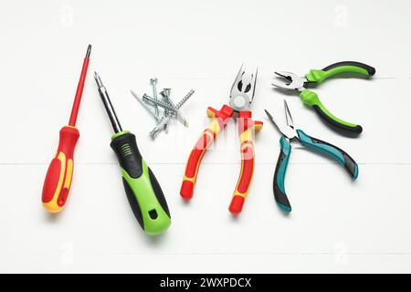 Pliers, screwdrivers and screws on white wooden table, flat lay Stock Photo