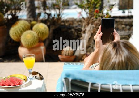 Woman using cellphone while relaxing on terrace in resort Stock Photo
