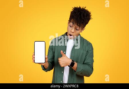 Surprised young man holding smartphone Stock Photo