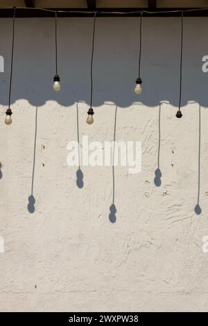 Some hanging bulbs cast their shadow on a white wall in the afternoon, in the colonial town of Villa de Leyva in central Colombia. Stock Photo