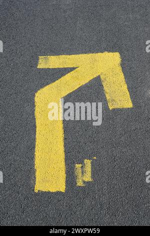 A yellow arrow painted on black asphalt Stock Photo