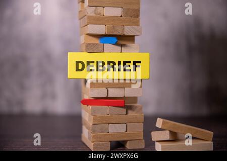 The inscription debrief in wooden cubes on a dark concrete background. Can be used as part of your composition. Stock Photo