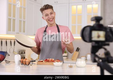 Smiling food blogger explaining something while recording video in kitchen Stock Photo