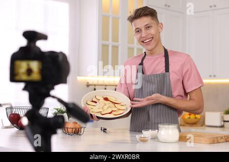 Smiling food blogger explaining something while recording video in kitchen Stock Photo