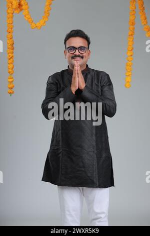 A man with Indian traditional costume, with plain background, isolated, wearing black kurta and white pajama. Stock Photo