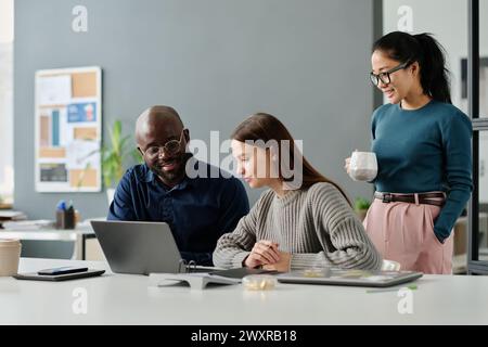 Group of three ethnically diverse male and female managers working on business project in modern office, copy space Stock Photo