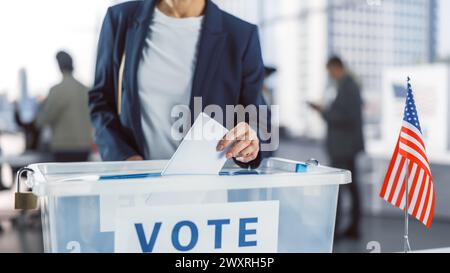 American People Visiting a Polling Station on Elections Day in the Capital Of United States of America. Female Caucasian Voter Casting Her Vote and Putting Ballot into a Transparent Sealed Box Stock Photo